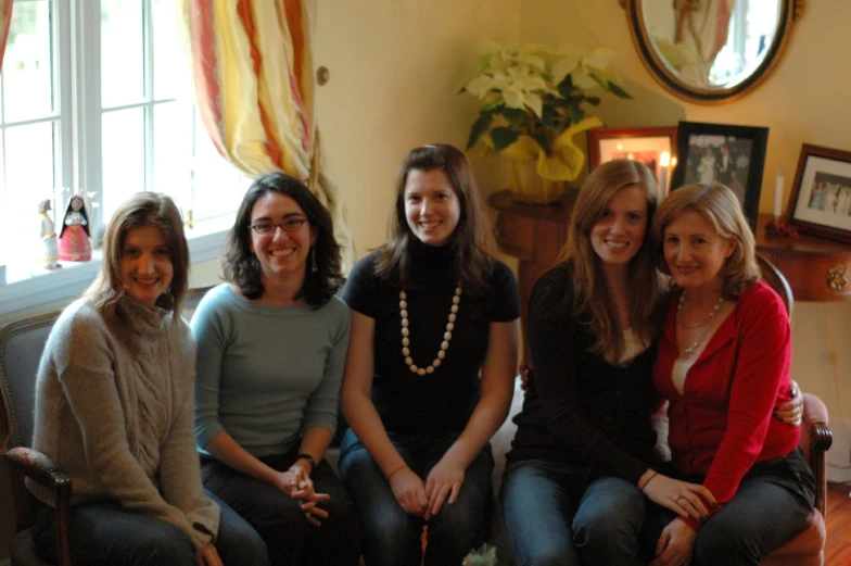 five women sitting on a couch smiling at the camera