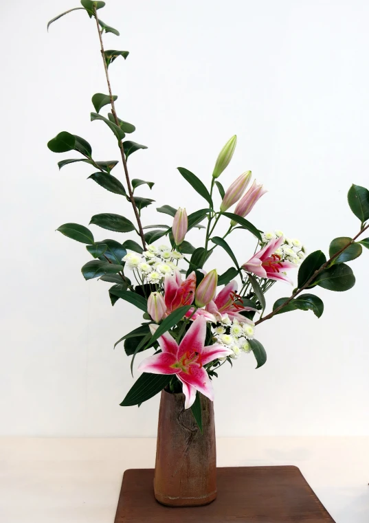 a vase filled with flowers and greenery on top of a wooden table