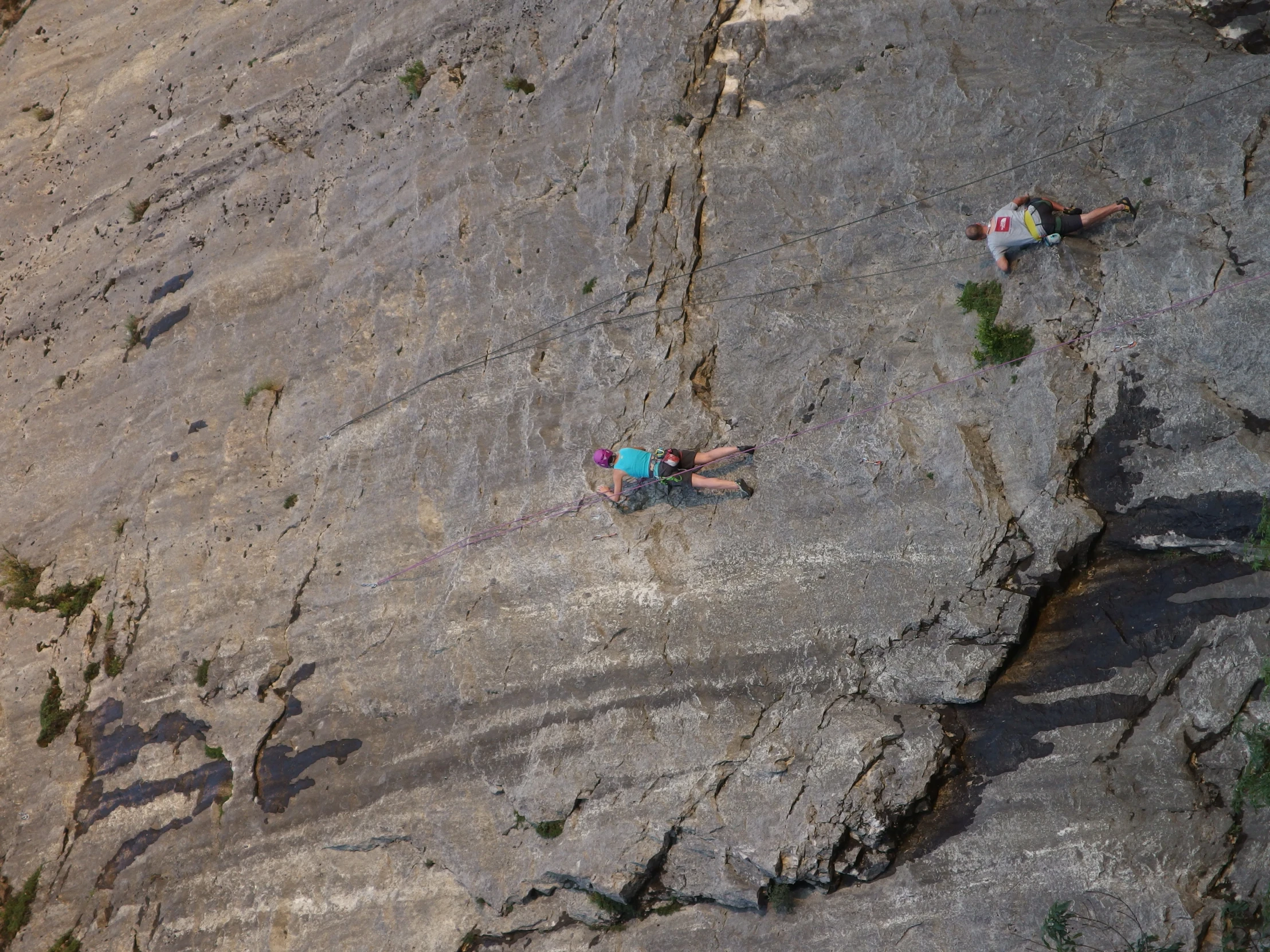 two climbers scaling up a steep, rocky wall