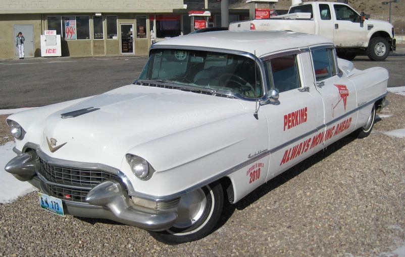 an old style white truck parked in the middle of a parking lot