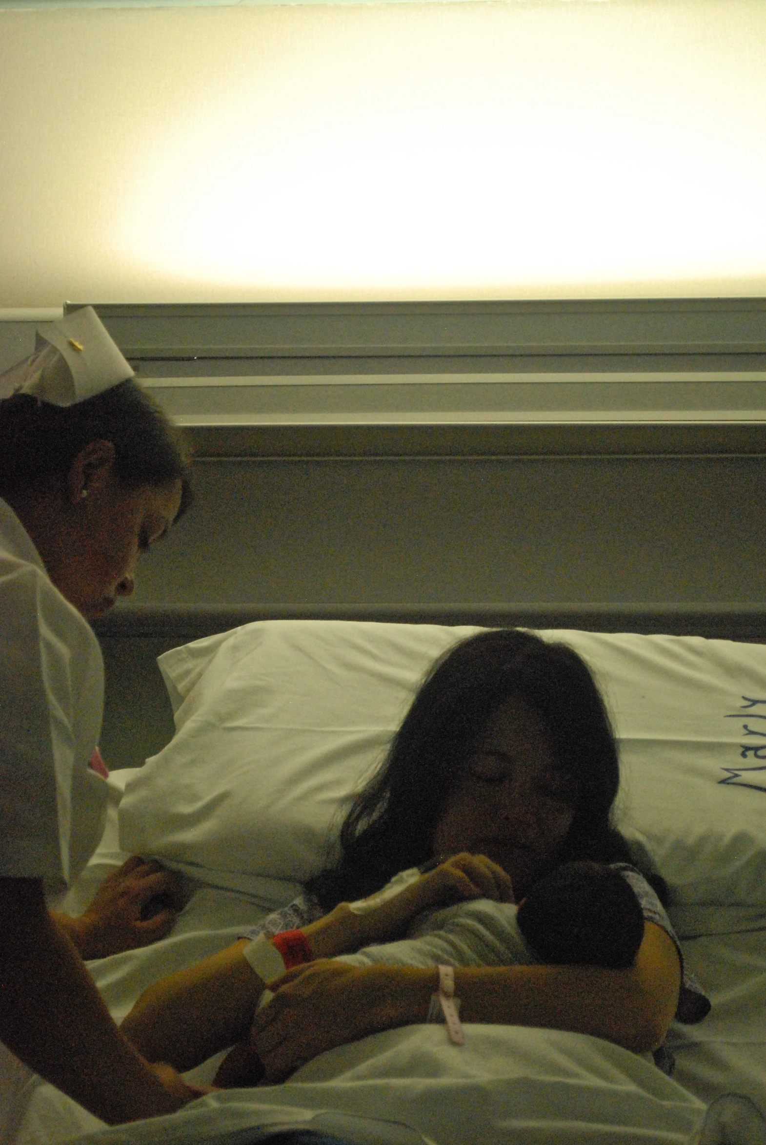 a woman laying in bed while another nurse watches