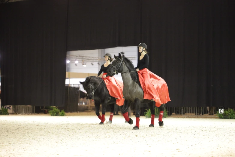 two women riding on horses around an arena