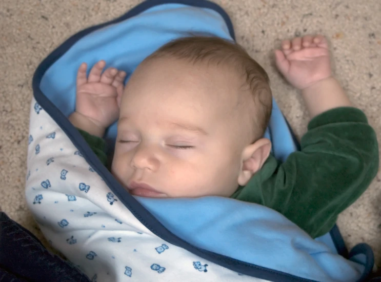 a baby is sleeping with his arm extended over its head