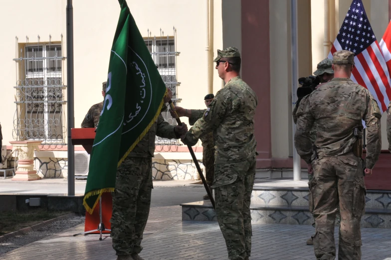 men in army fatigues are holding a flag and standing near other men