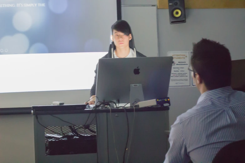 a man standing in front of a projection screen while someone sits in front of him