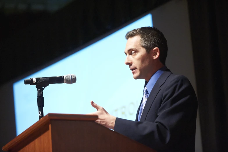 a man that is giving a speech with his hand out