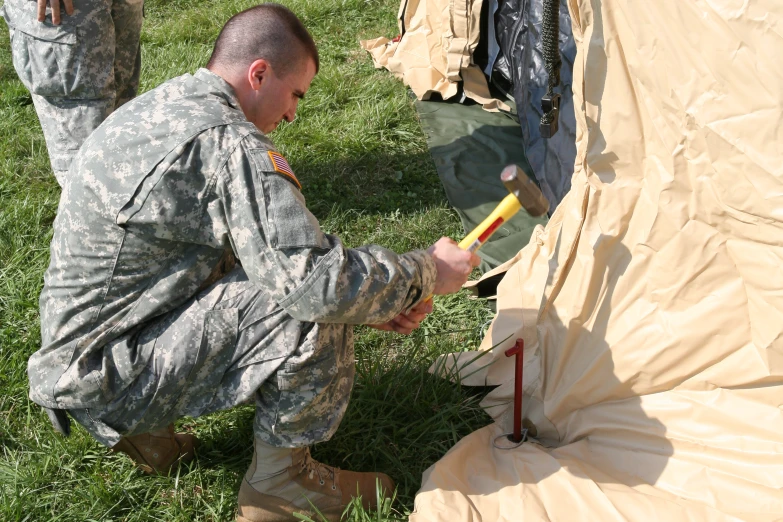 a man kneeling down near a tent preparing to use the hose