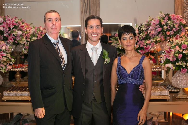 two men and a woman pose for a po at a formal event