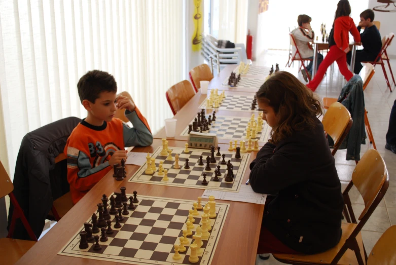 there are two boys sitting at the table playing chess