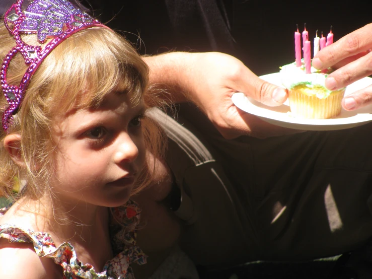 the little girl is eating the cupcake at the birthday party