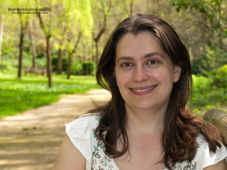 a smiling young woman with a green park in the background