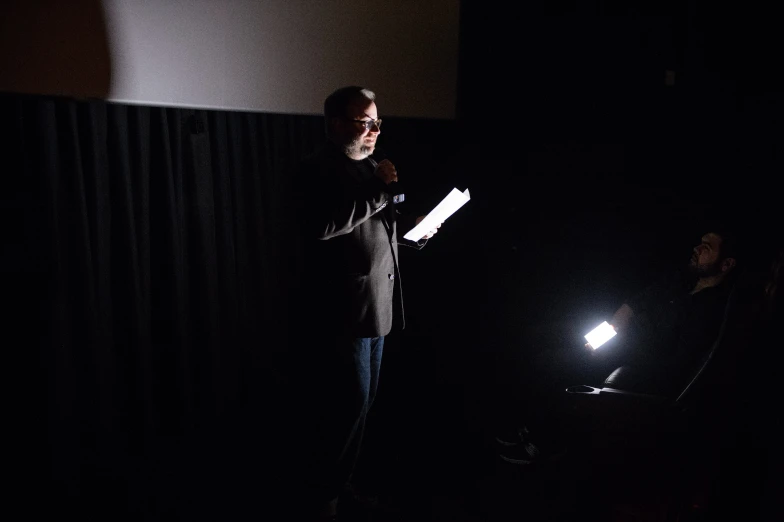 a man is talking on stage in the dark
