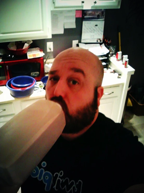 a bald man is eating ice cream in his home kitchen