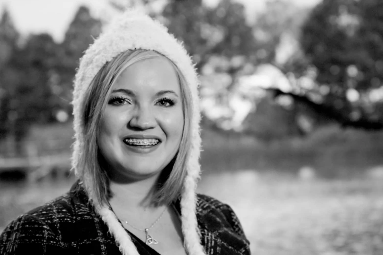 a woman wearing a fur hat with trees in the background