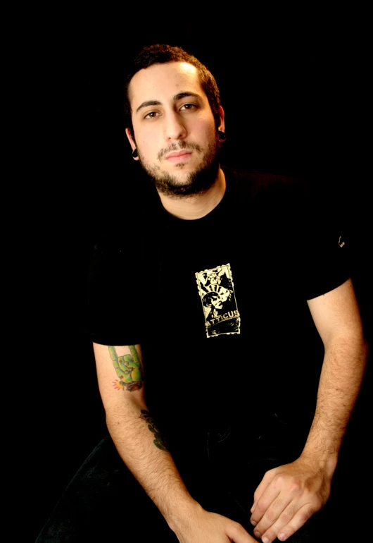 a man with tattoos sitting down and smiling