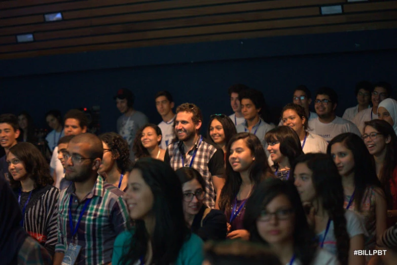 a group of people sit together smiling while another man watches