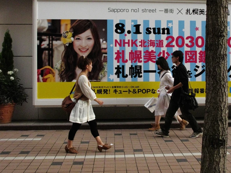 a girl walks past posters advertising the upcoming news