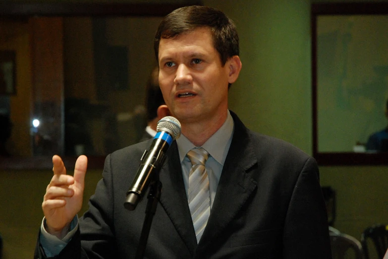 a man in suit speaking into a microphone