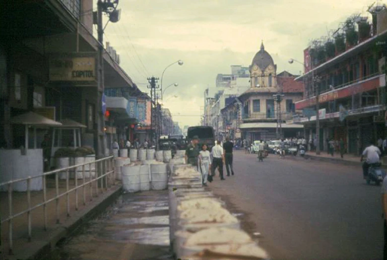 people walking down a road in front of tall buildings