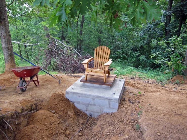 two wooden chairs sitting next to a rock fireplace in a forest