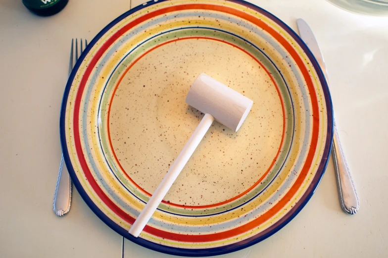 a dinner plate with a colorful plastic spoon and fork