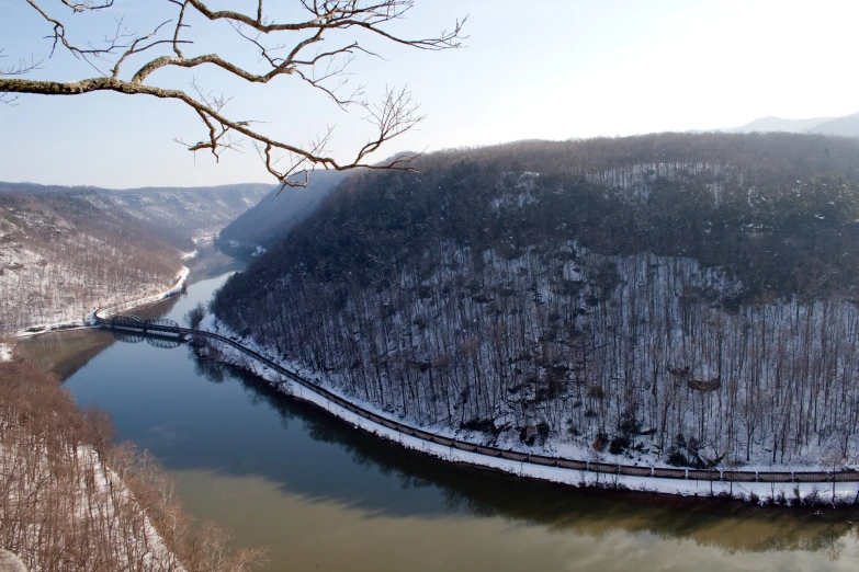 a mountain view of a river, some snow and trees