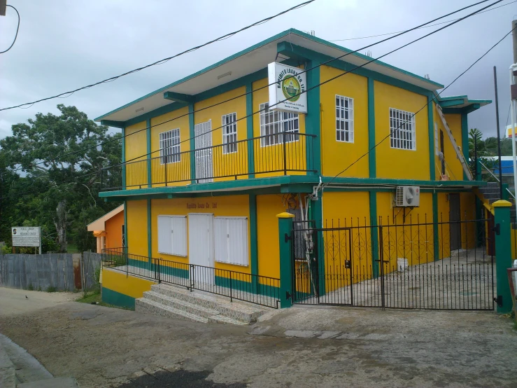 an empty road and a yellow building with green trim
