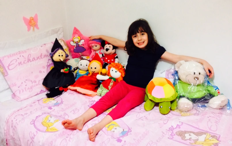 little girl with her stuffed animals and pillows on a pink bed