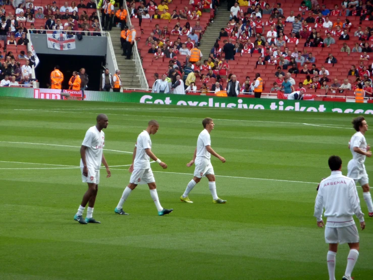 several soccer players walking across a field in front of an audience