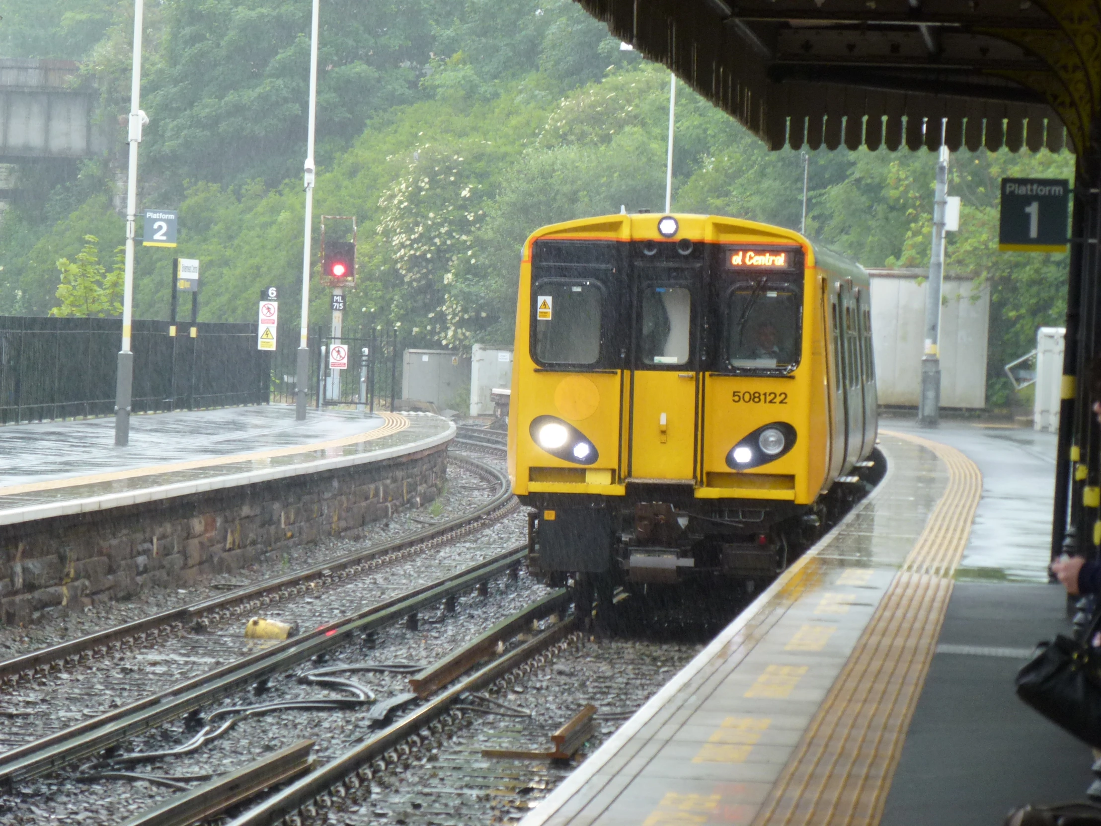 a yellow train on tracks near some houses