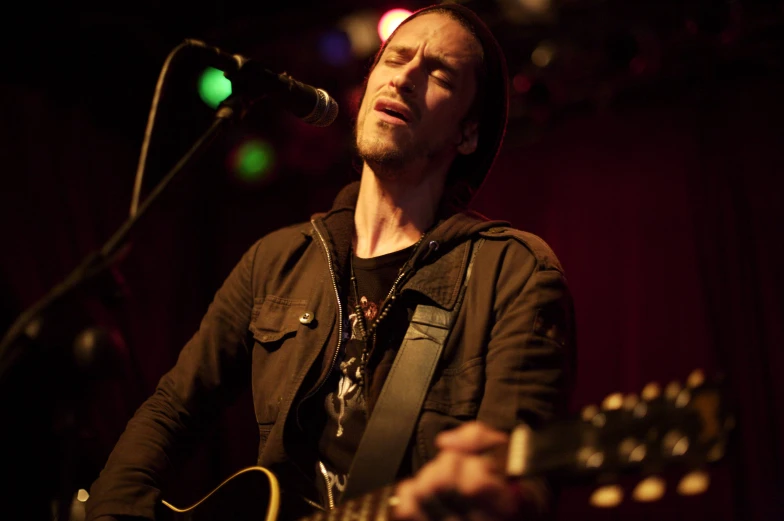 a man playing guitar in front of a microphone