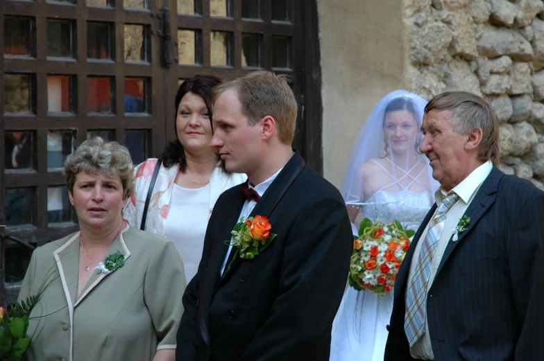 a bride and groom looking at each other with two older women and one younger man