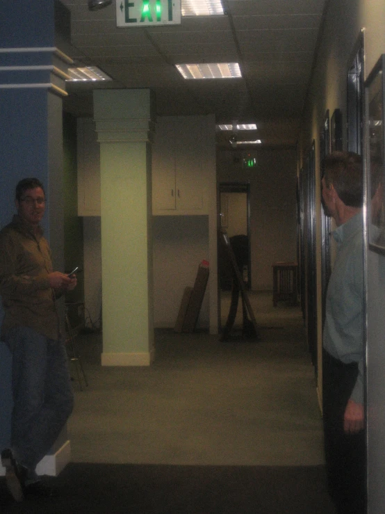 two people are walking down the hallway of a public building