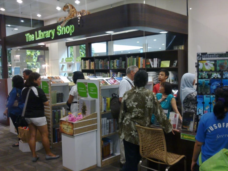 people standing inside of a book store with the shelves full