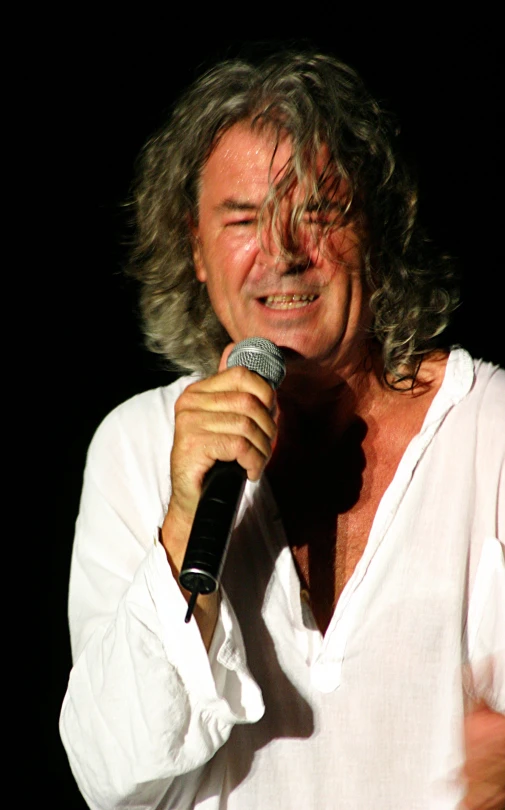 a person with an excited look on their face singing into a microphone