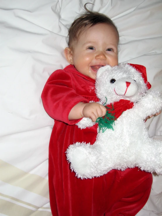 baby in santa outfit playing with stuffed animal