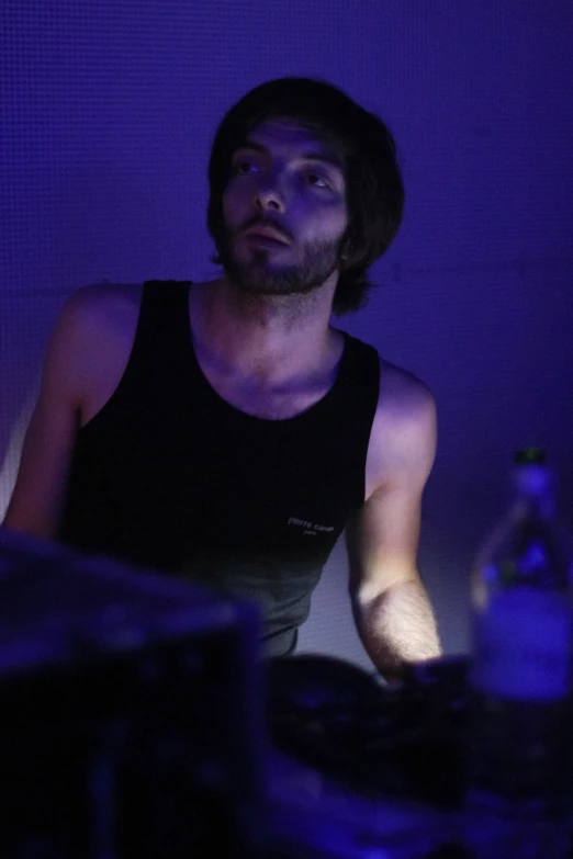 a man in a tank top in the dark at a party