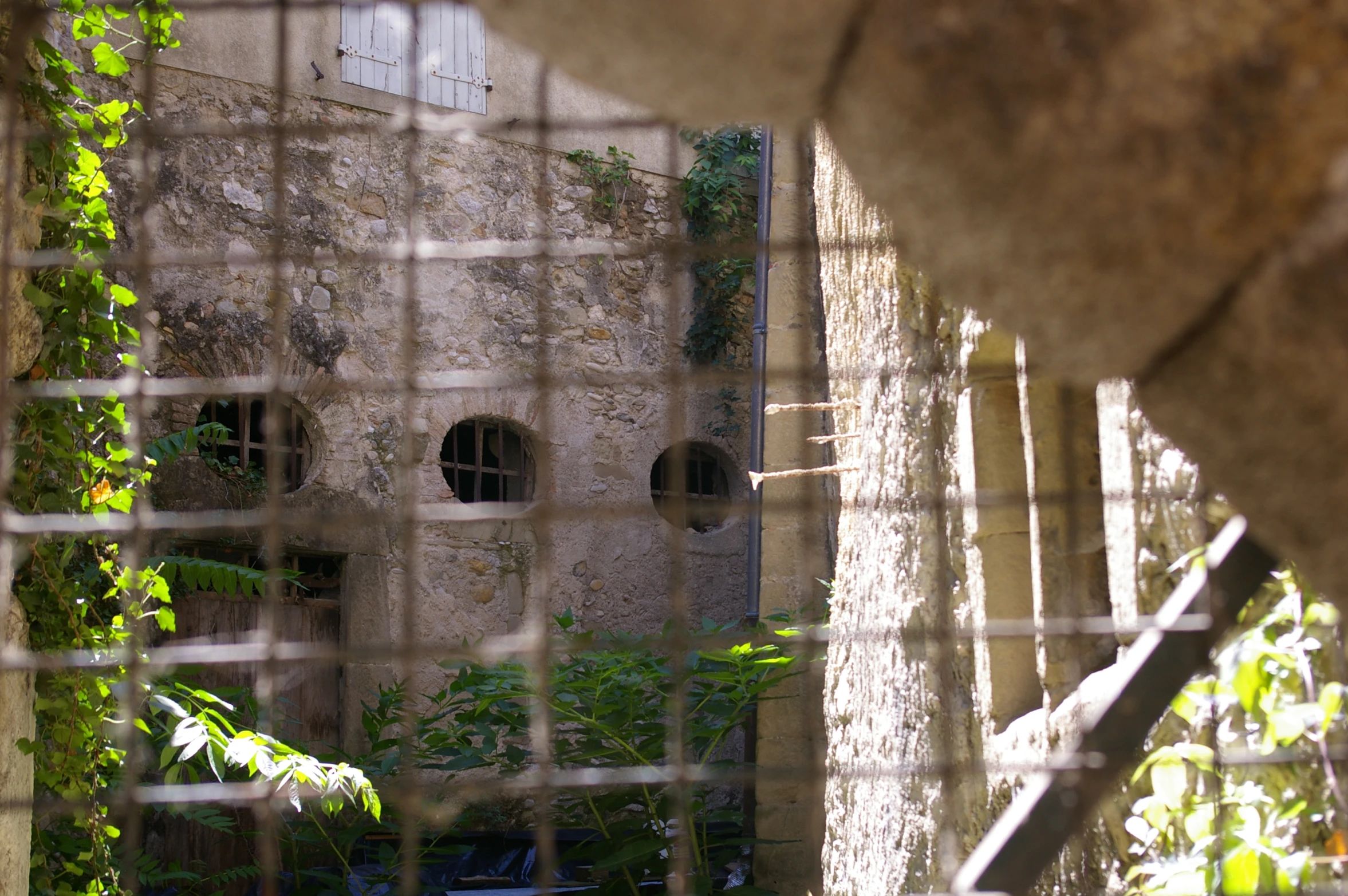 a stone building behind a gate with ivy growing on it