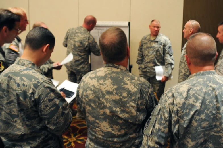 many men standing around in military uniforms and one holding papers