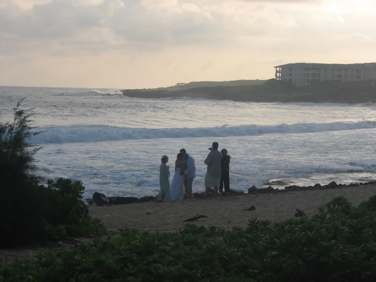 two men and a woman standing on a beach