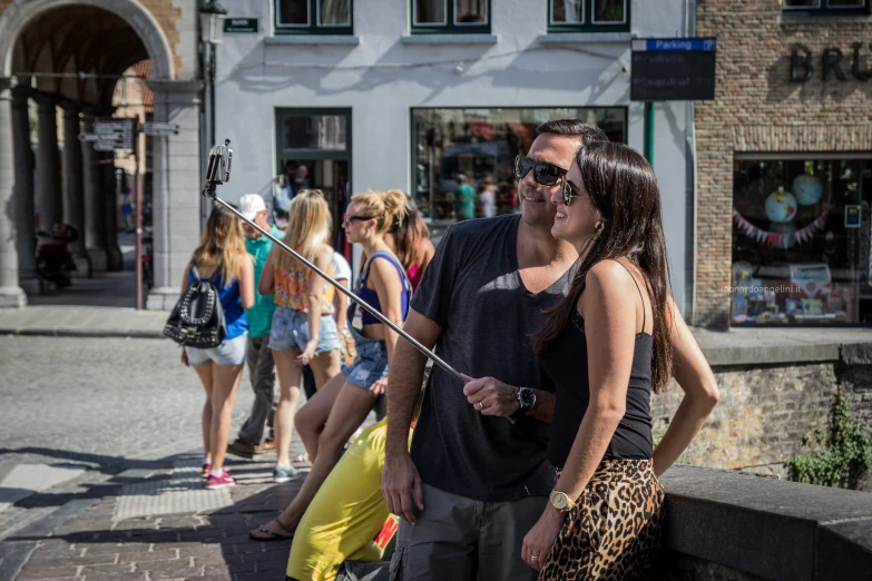 a woman on a sidewalk has an umbrella in the air and a man holds it as people look on