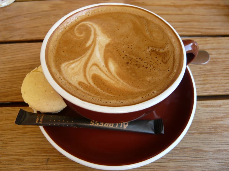 a chocolate cup filled with liquid on top of a red saucer