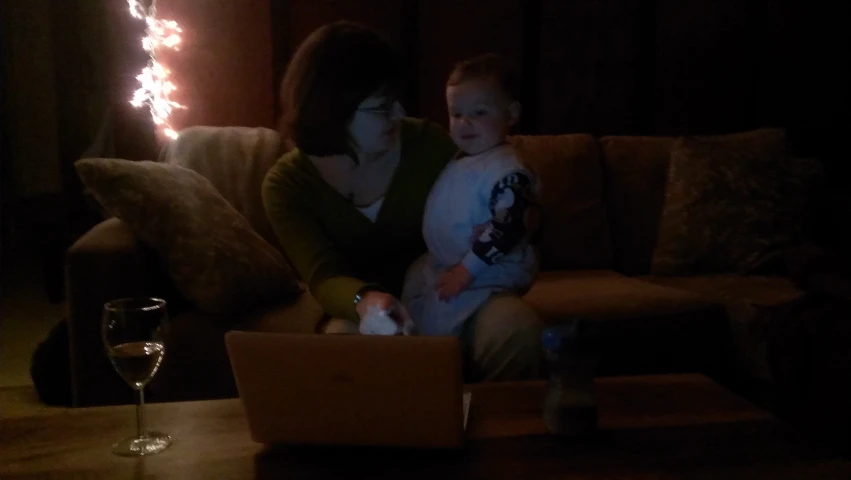 a woman and her son sitting on a couch in the dark