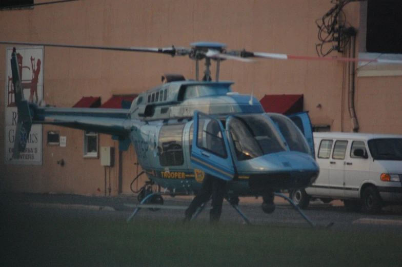 a blue helicopter parked in front of a building