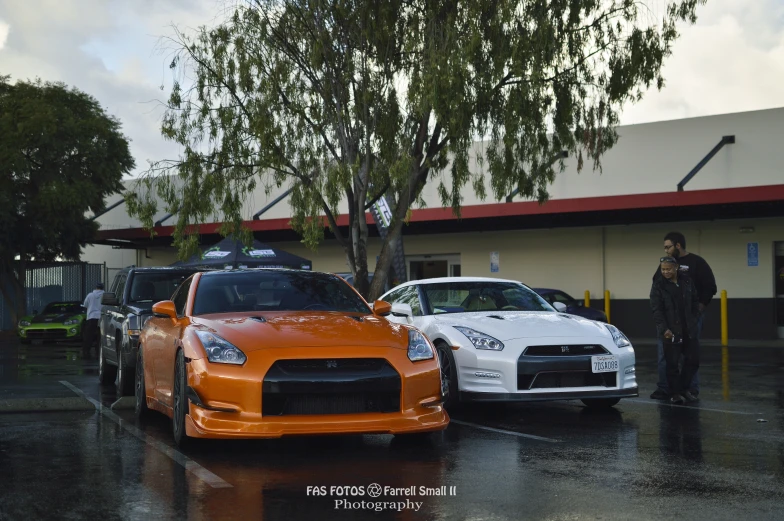 two cars parked on the side of the street as people with umbrellas look on