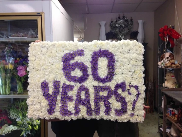 a large sign with words is covered in white flowers