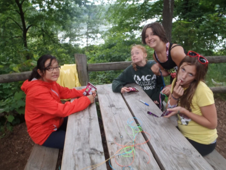 four young women standing around a picnic table