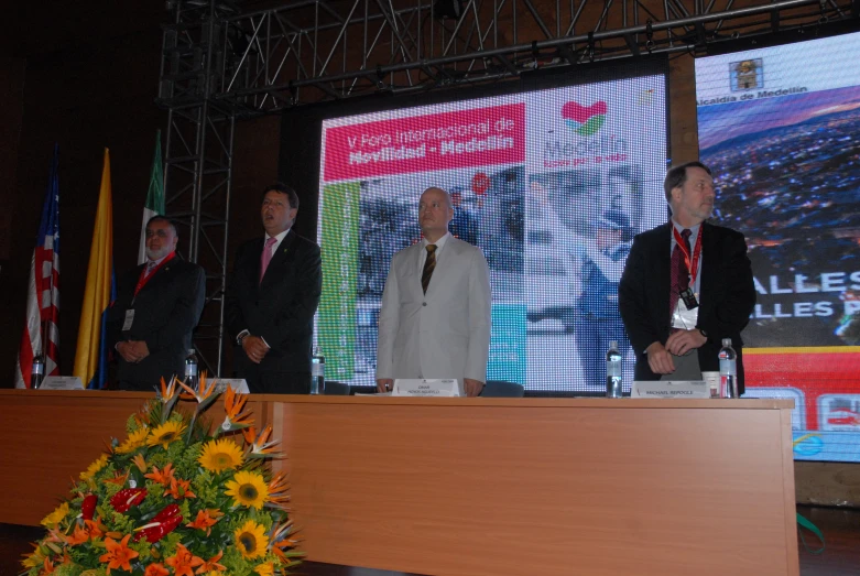 three men are speaking with a podium in front of them