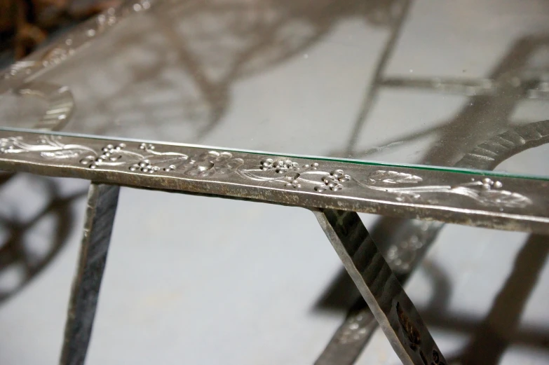 an artistic metal and glass table with ornate scrolls on top