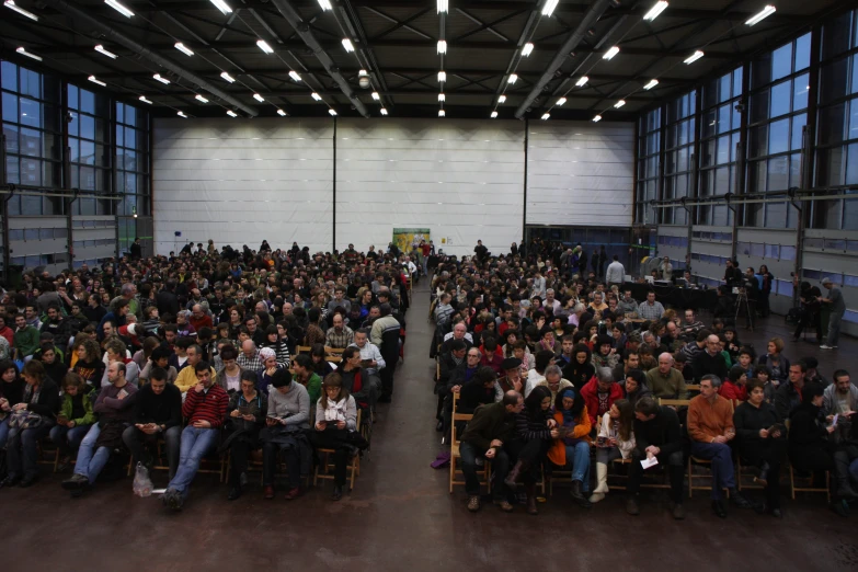 a crowd of people sitting in chairs inside a room